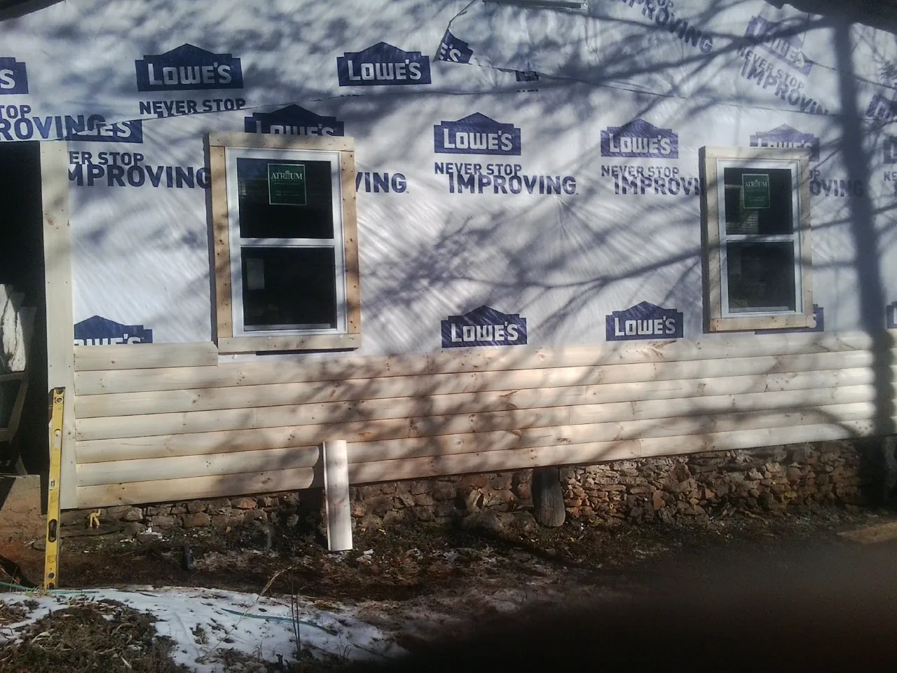 House wrap and new log siding going up on an exterior wall in Brownstown