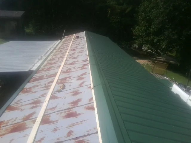 Old rusted panels beside newly installed green metal roofing — Wind Damage Roof Repair by Roofing Brothers in Brownstown