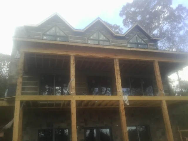 Dormers and porch framing on a large log home under construction — Roof Coating work by our crew in Brownstown