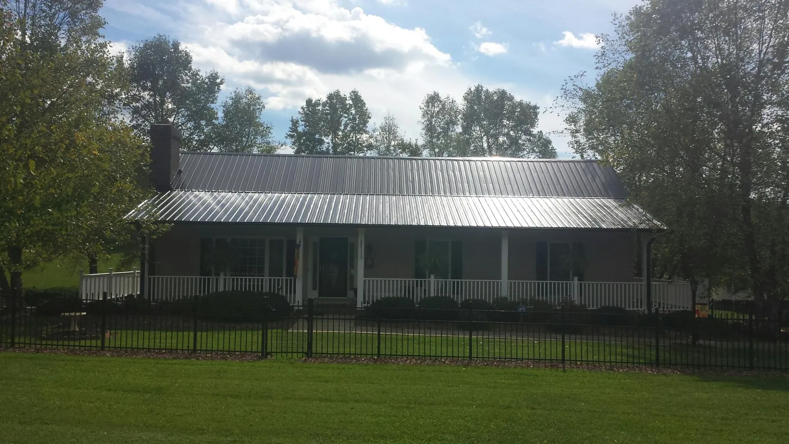 Gray metal roof on a brick ranch with a full width front porch — Gutter Guard Installation work by our crew in Brownstown