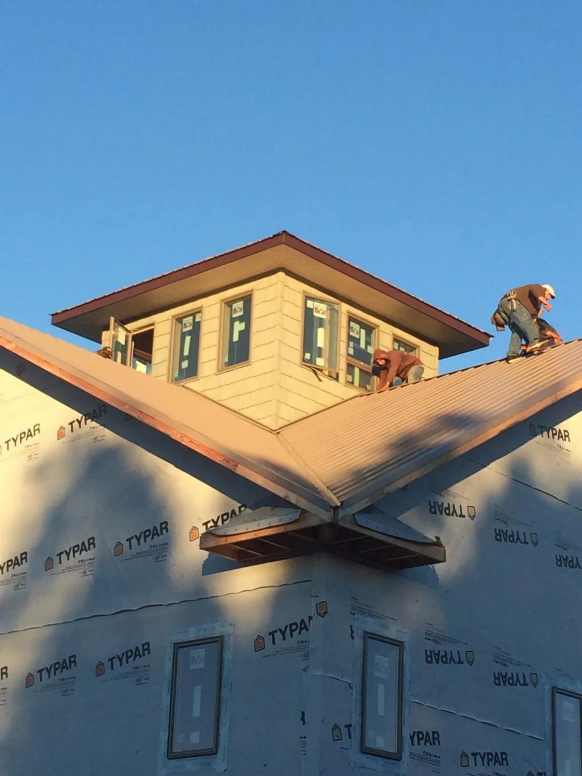 Roofers working around a rooftop cupola on a new metal roof at sunset — Roof Waterproofing in Brownstown by Roofing Brothers